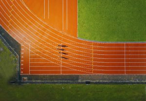 coureurs sur la ligne de départ d'une piste d'athlétisme vue de haut — cycles commerciaux et structuration de l'intensité